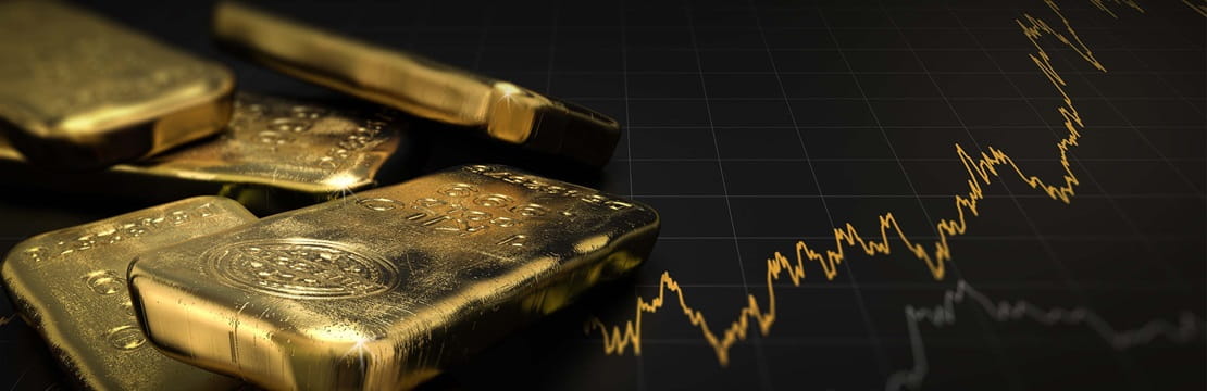 A stack of gold bars sits next to a gold-colored image of a stock market graph