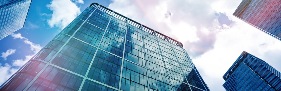 Low angle view of financial district buildings with sunny skies in background