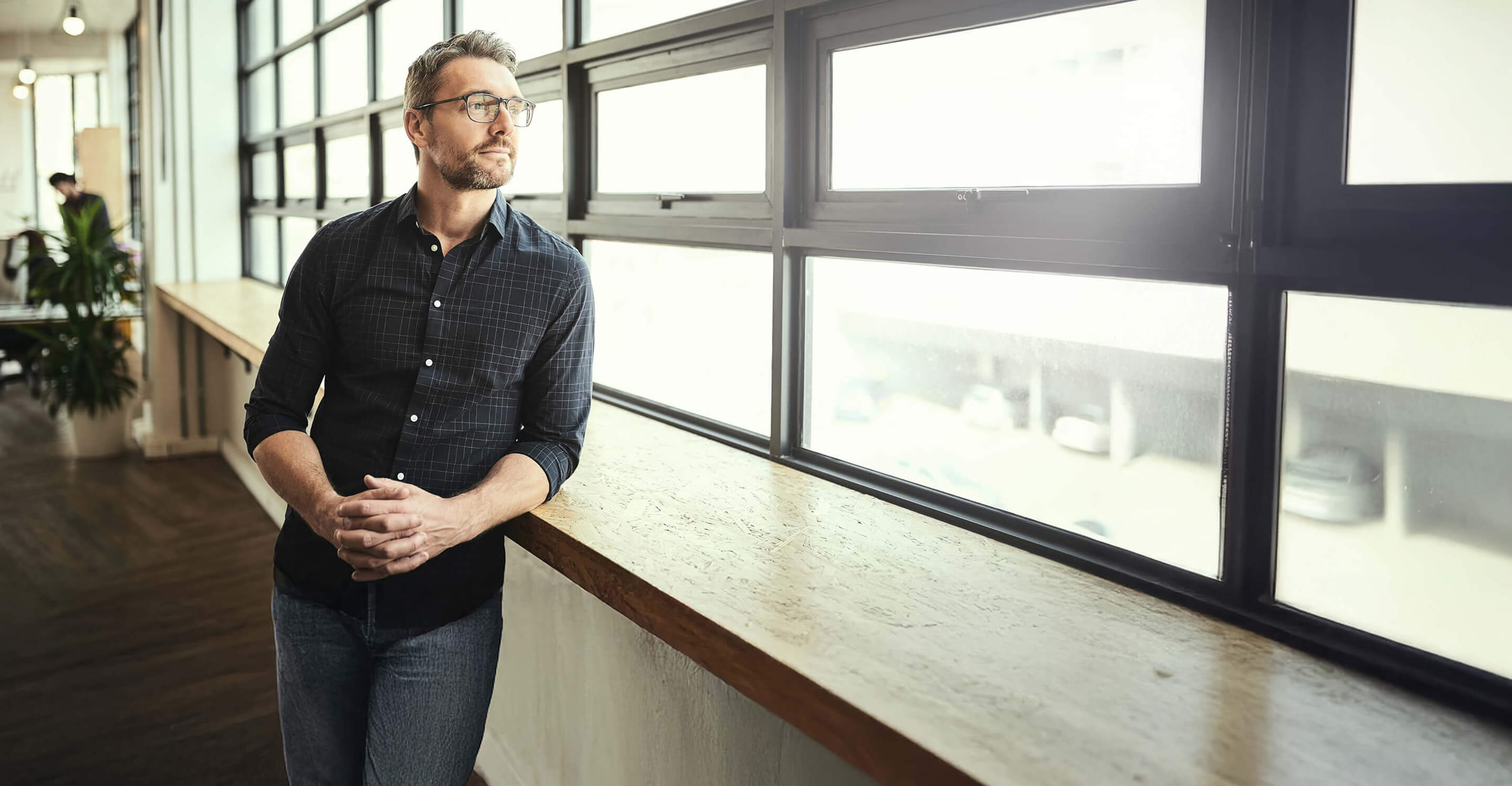Business man looking out of a building window.